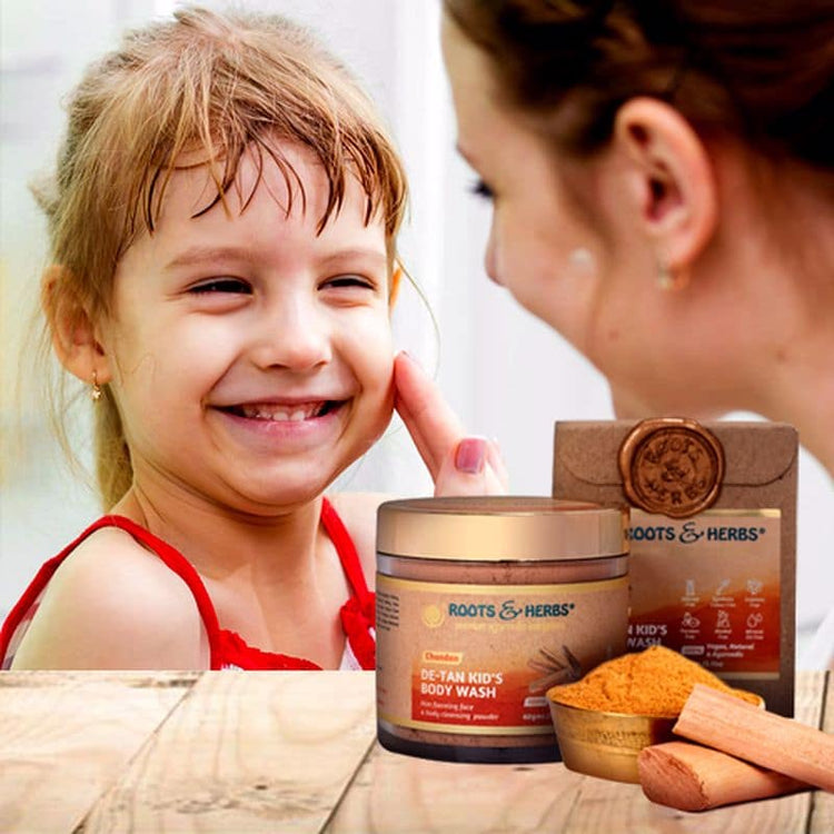 Mother gently touching her smiling daughter's cheek beside Roots & Herbs' Chandan De-Tan Kid's Body Wash